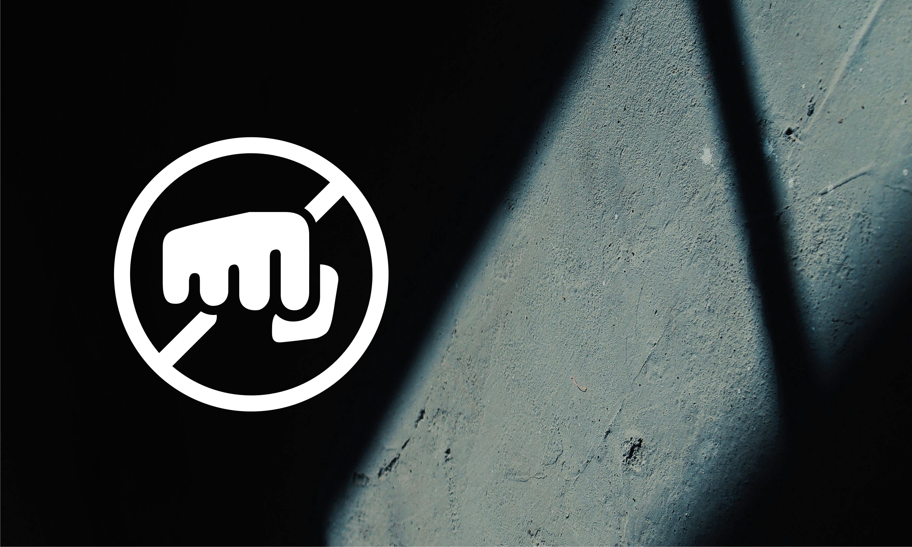 clenched fist in a crossed out circle, rough cement wall in the shadow